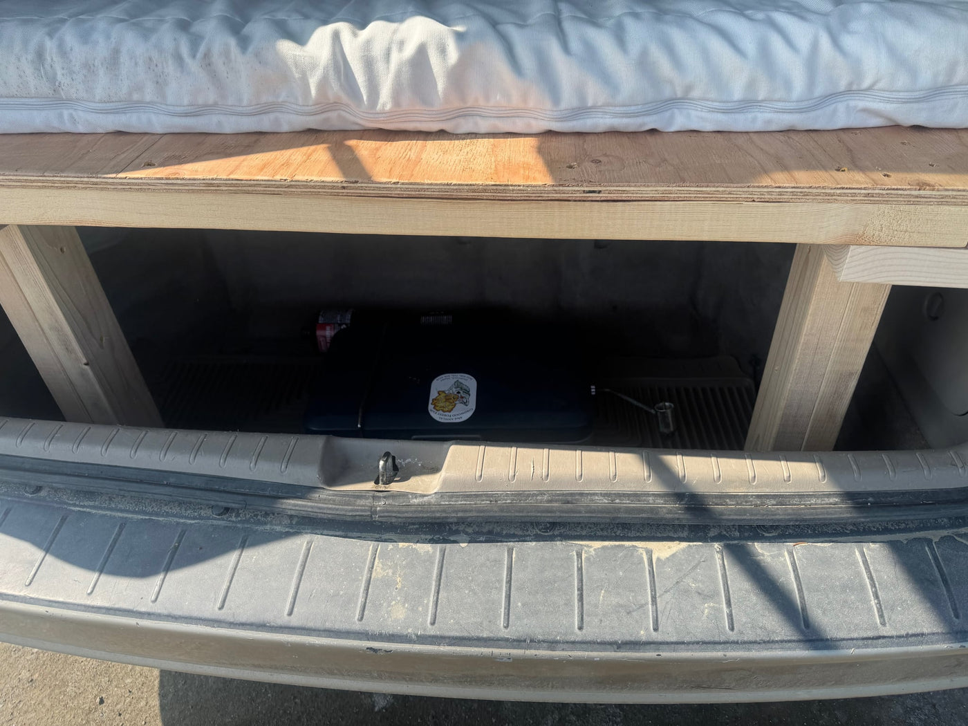  showing a built-in bed by the ocean. A tractor is nearby.|Gold Toyota Sienna minivan with roof cargo box — photo 14