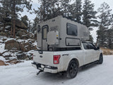 Winter wonderland ready: Ford F-150 with a Scout Yoho truck camper on a snowy road. Perfect for your next rv rental.