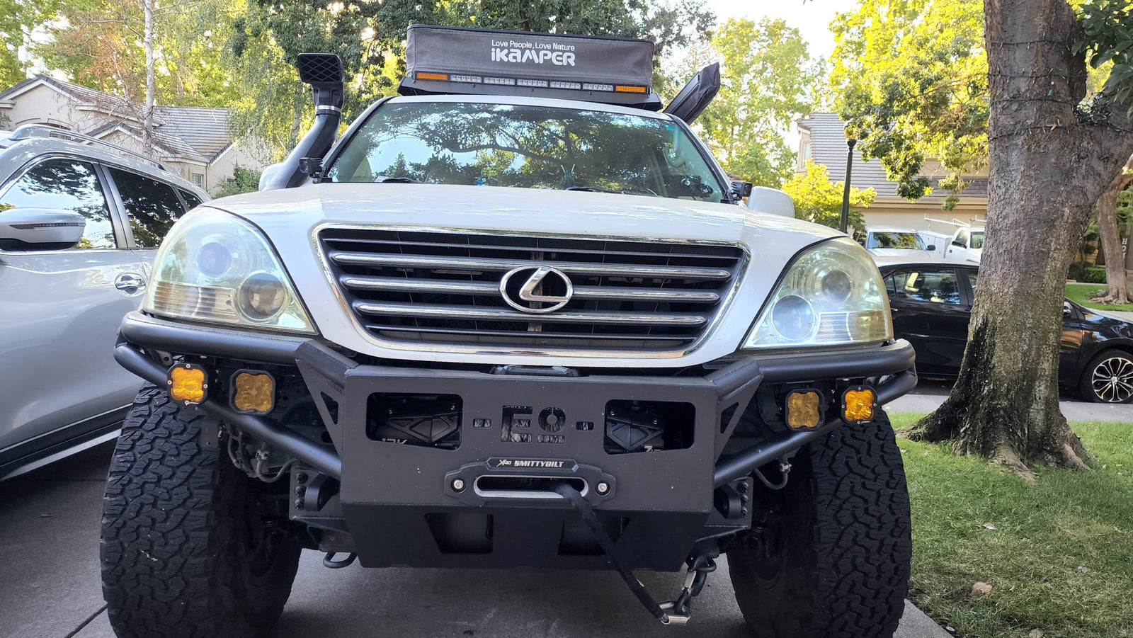 Front view of a white, modified Lexus GX with an iKamper rooftop tent & winch. An ideal off-road rv rental for adventure trips.