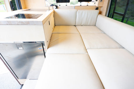 Comfortable RV rental interior: L-shaped seating, modern kitchenette with cooktop and built-in fridge.