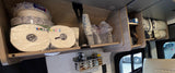 RV rental overhead cabinets neatly stocked with paper plates, cups, paper towels, and pillows, showcasing efficient travel storage.