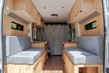 Spacious custom RV rental interior featuring wood paneling, comfortable benches, and a full kitchen setup.