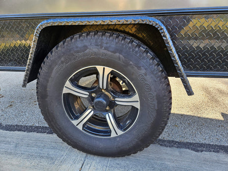 Close-up of a rugged tire and wheel on an rv rental trailer, featuring Goodyear Radial tire and diamond plate fender.