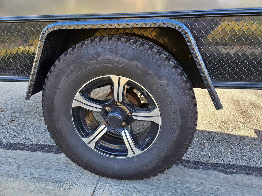 Close-up of a rugged tire and wheel on an rv rental trailer, featuring Goodyear Radial tire and diamond plate fender.