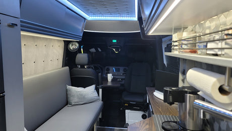 Spacious RV rental interior with bright LED lighting, showing kitchen, seating, and front cabin setup for travel.