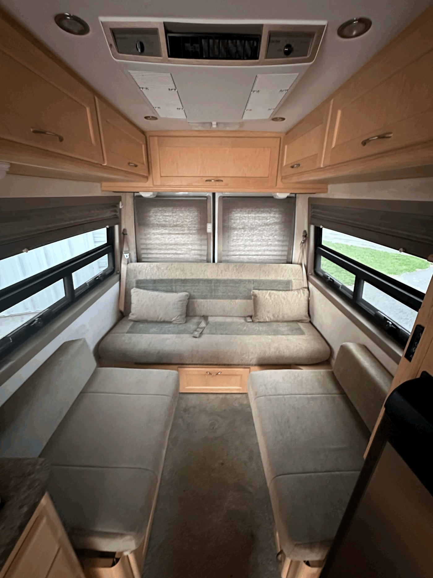 RV rental's inviting interior: featuring a versatile sofa bed, two separate seats, wood cabinets, and large windows. — photo 6