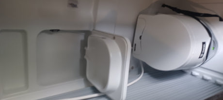 RV rental storage with a secured portable power station (green light visible) and a white charging device connected by a cable.