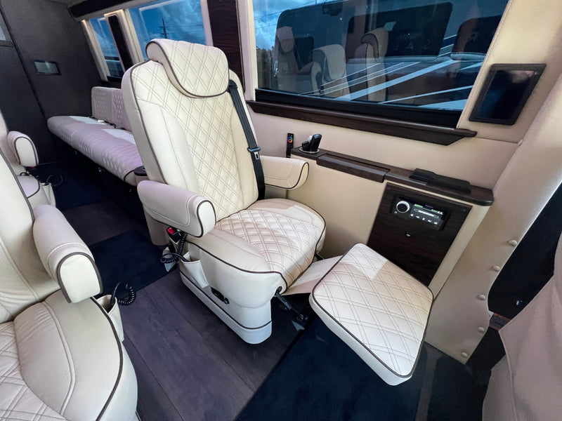 Luxury RV rental interior with cream quilted leather seating, extendable footrest, and integrated entertainment controls for ultimate travel comfort. — photo 5