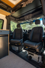 Modern rv rental interior: Driver's view with swivel seats, overhead storage, microwave, and fridge.