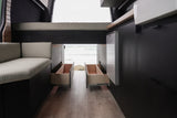 Modern RV rental interior with open back, showing beach view, bench seating, and pull-out storage drawers.