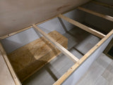 RV rental interior: Under-bed storage area with light wood framing, OSB platform, and light-toned flooring.