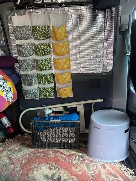 RV rental interior: Smart storage with hanging pockets, insulated windows, portable commode, and crate organization.