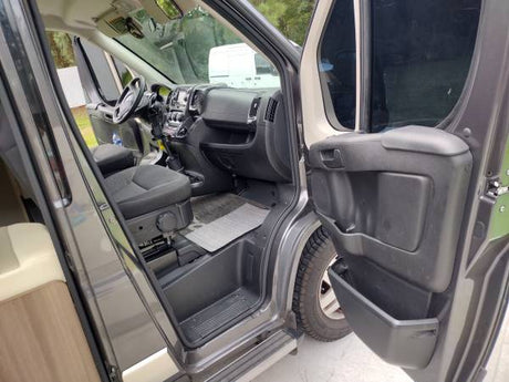 Detailed view of an RV rental's spacious cabin, showing the driver's seat, dashboard, and open passenger door.