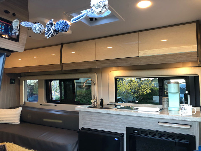 This modern RV rental's interior features a well-equipped kitchen, overhead cabinets, and a cozy living area. — photo 8