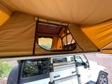 View from below an open rooftop tent on a white Jeep Wrangler, an agile RV rental alternative for overland camping adventures.