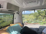 Inside a comfy rv rental, enjoy a scenic view of nature, mountains, and a lake from the bed.