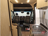 Step inside this RV rental: front cockpit with driver/passenger seats, a clear view forward, and a compact kitchenette on the right.
