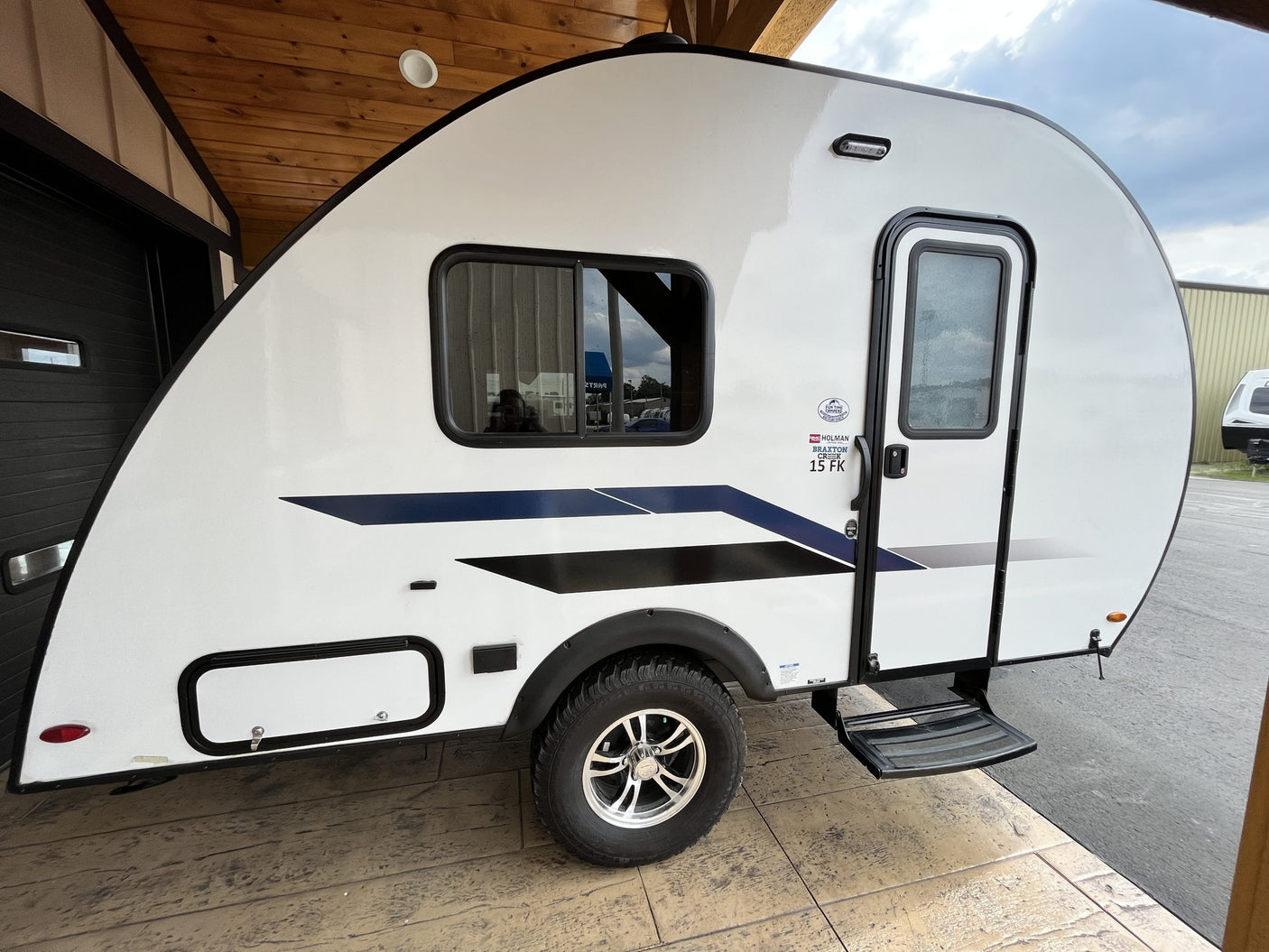 White Braxton Creek 15 FK travel trailer with black/blue graphics, ideal for your next RV rental.