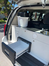 Explore this RV rental's clever campervan kitchen, featuring a sink and open Dometic fridge drawer in the rear.