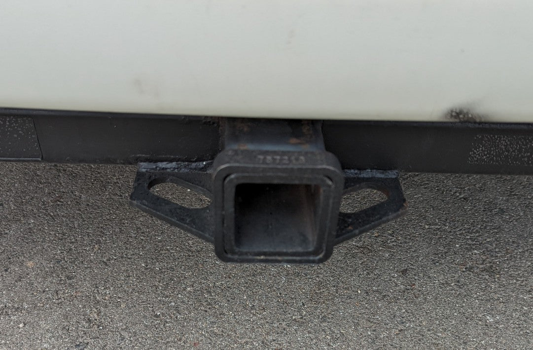 RV rental: Close-up of black vehicle hitch receiver with safety chain loops, essential for towing trailers.