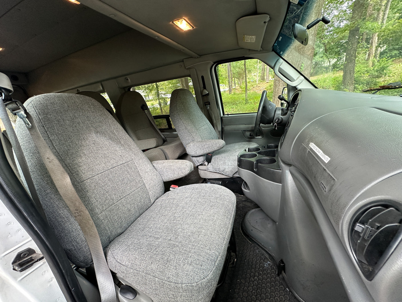 Inside an RV rental van: light grey fabric seats, detailed dashboard, and bright cabin lights, set for comfortable travel.
