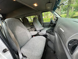 Inside an RV rental van: light grey fabric seats, detailed dashboard, and bright cabin lights, set for comfortable travel.