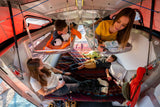 Family relaxing inside a spacious RV rental, complete with cozy bunks and a comfy main bed for a perfect adventure.