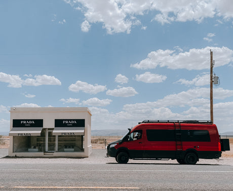 Red RV rental van at Prada Marfa desert art installation. Driver waves from the window.