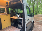 Cozy camper van interior with kitchen and dining, perfect for an RV rental adventure in nature.