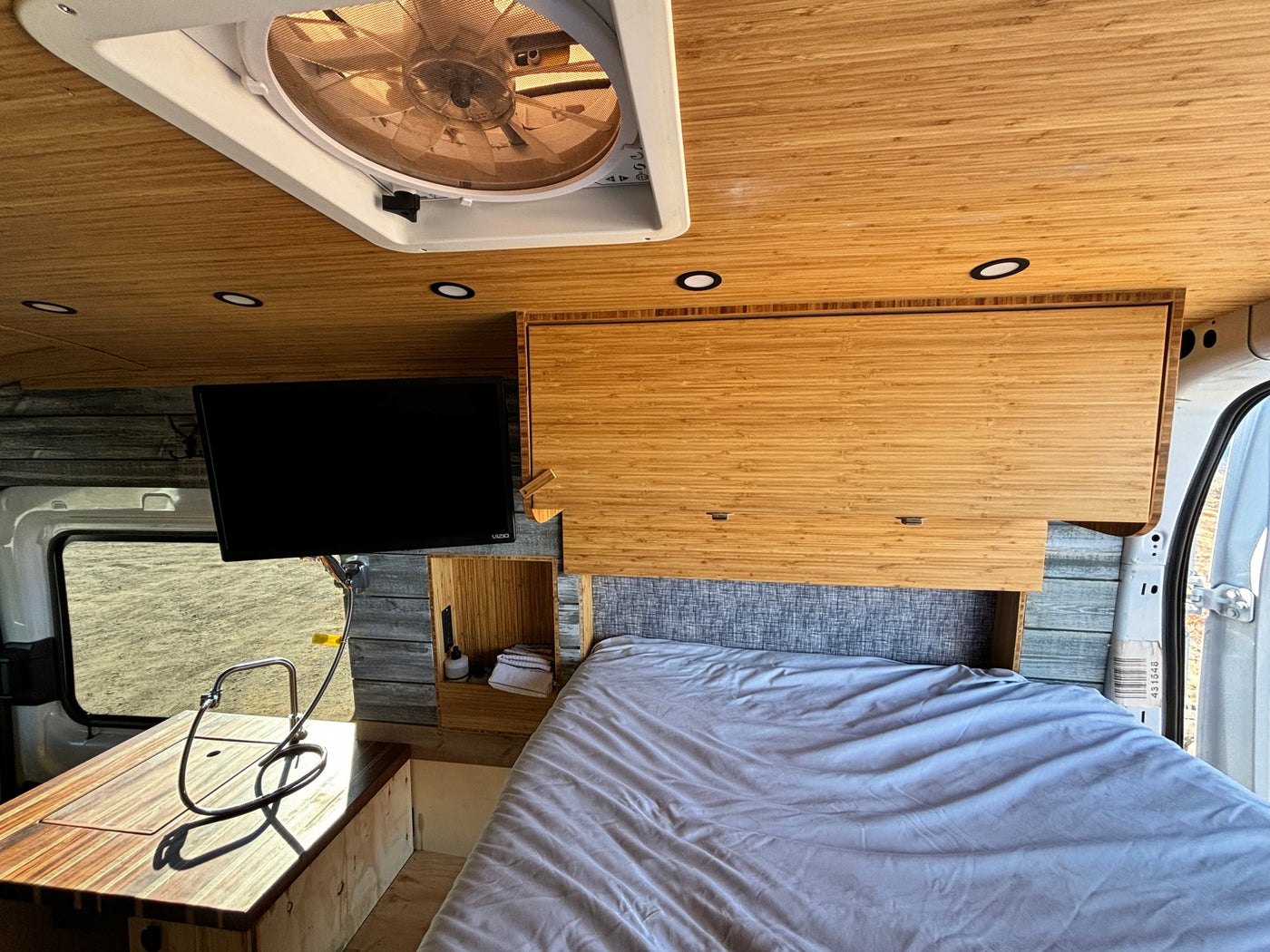 Experience comfort in this RV rental! Interior shows a bamboo ceiling, ventilation fan, TV, kitchen area, and a large bed. — photo 14