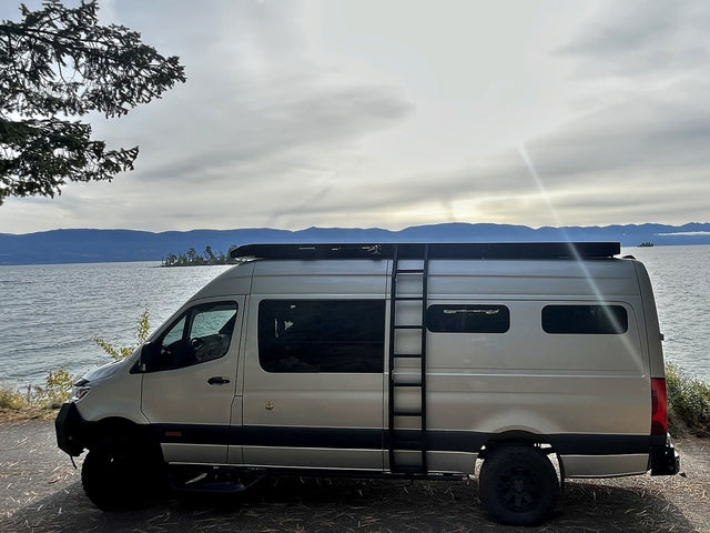 Light-colored rv rental van parked lakeside