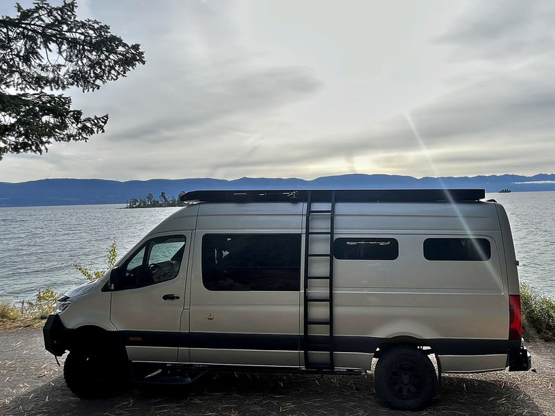 Light-colored rv rental van parked lakeside — photo 1