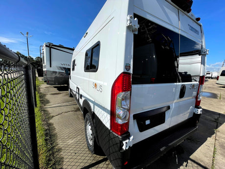 White Winnebago Solis camper van, ideal for your next RV rental adventure. Parked outdoors with fence shadows on concrete.
