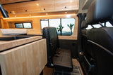 RV rental interior with custom wood cabinets, kitchen sink, bed, and passenger seats, showcasing a desert view.