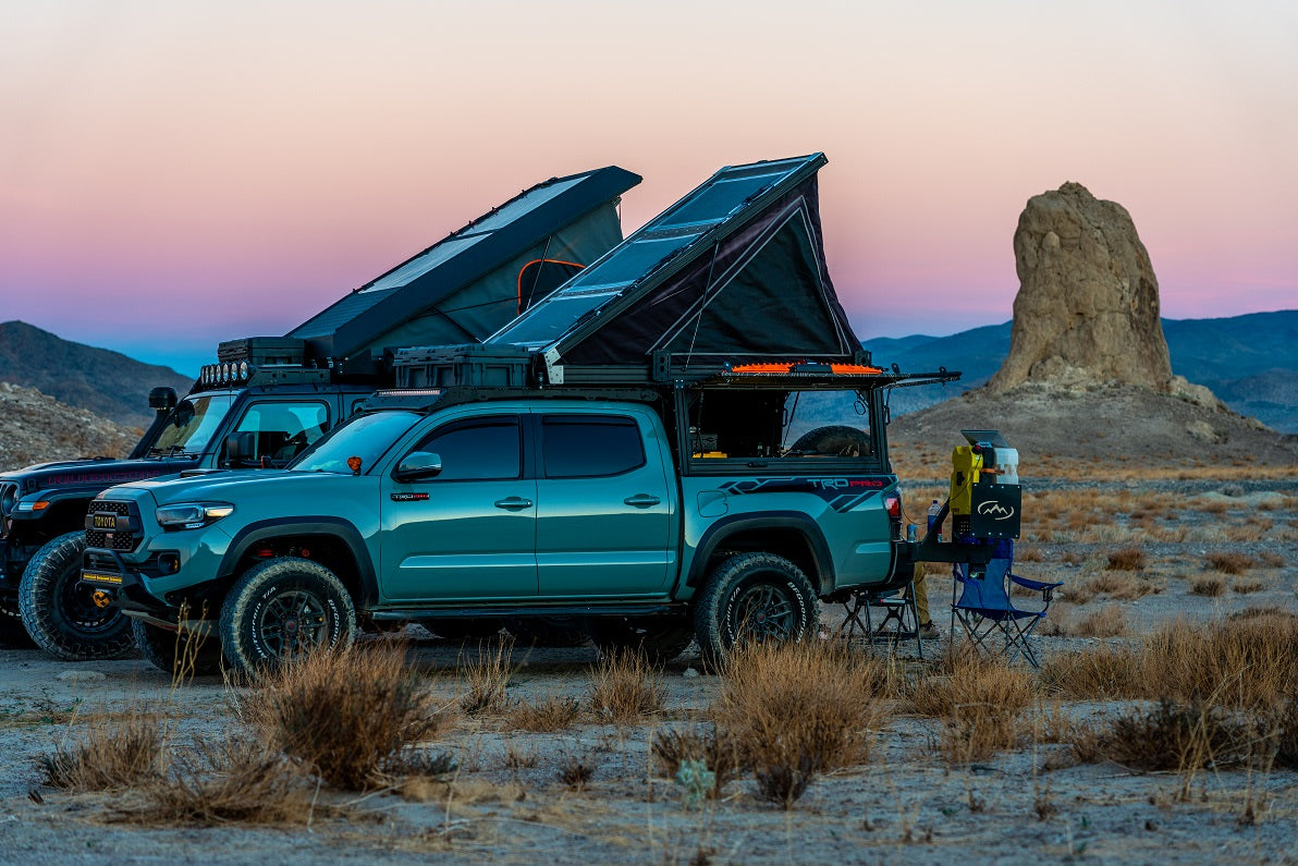 Overland RV rental vehicles with rooftop tents parked at dusk in the desert, equipped for adventure camping.