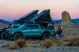 Overland RV rental vehicles with rooftop tents parked at dusk in the desert, equipped for adventure camping.