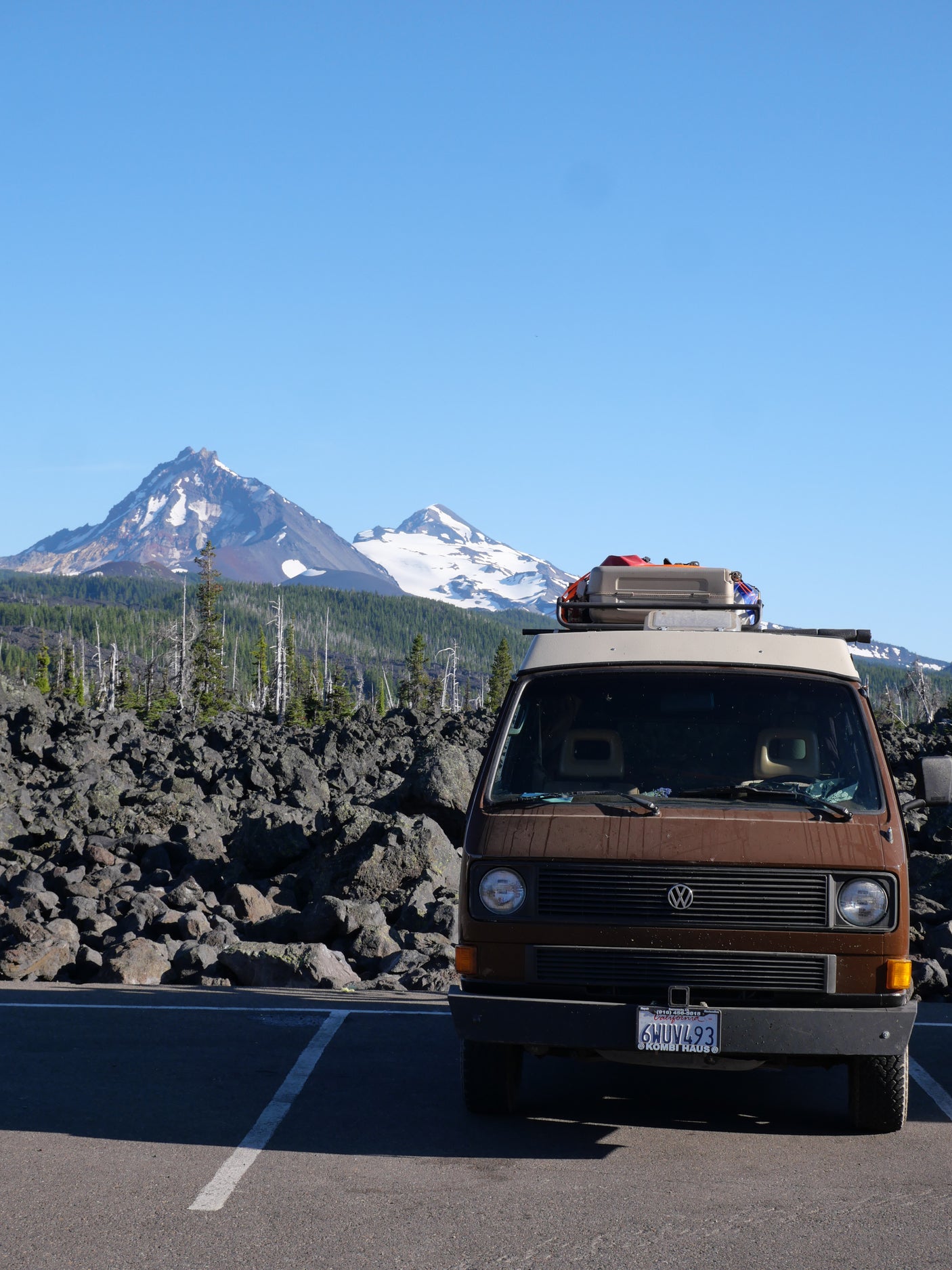 Brown RV rental van parked against a stunning backdrop of snowy mountains and volcanic rock.