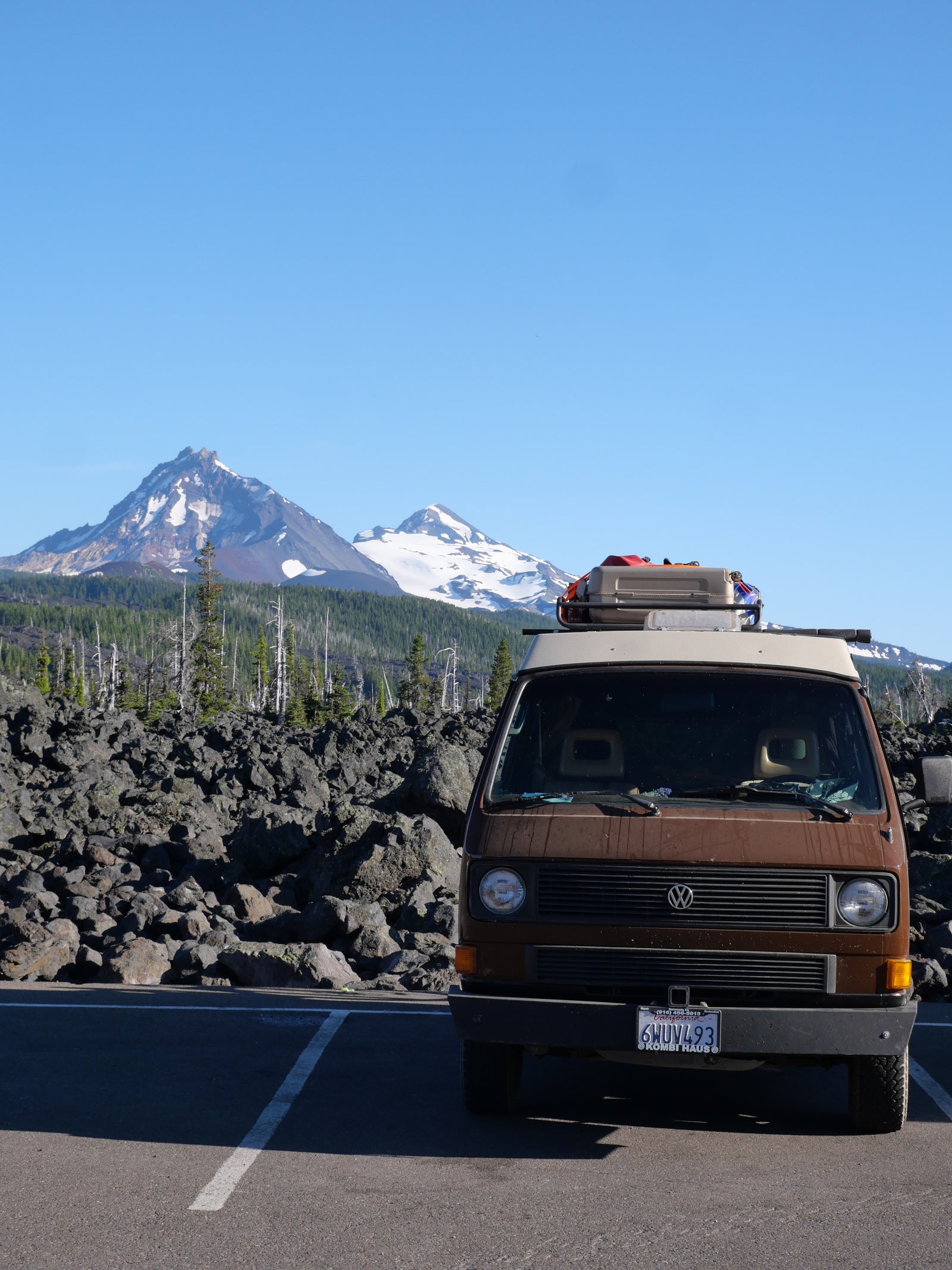 Brown RV rental van parked against a stunning backdrop of snowy mountains and volcanic rock.