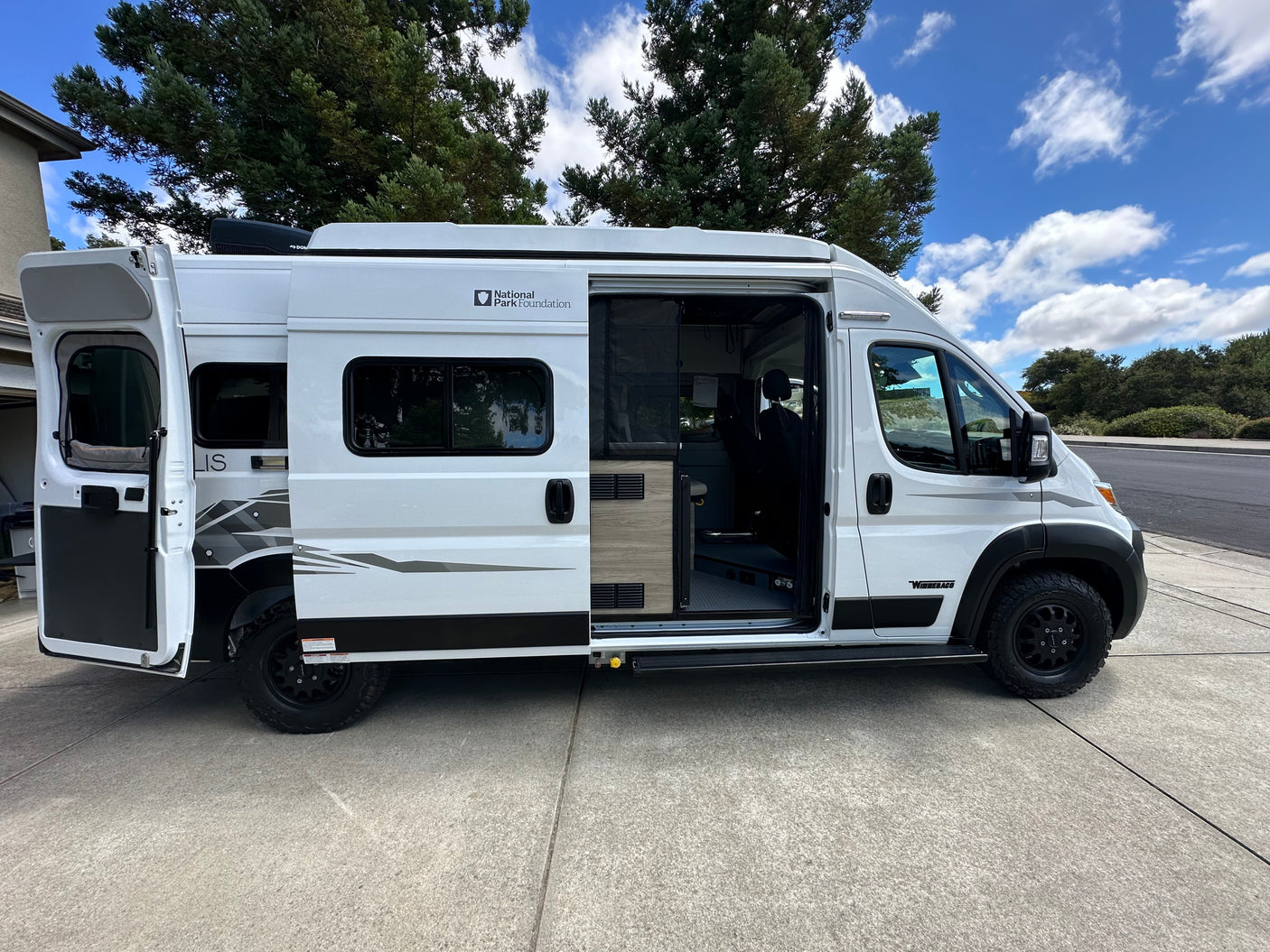 Modern white Winnebago camper van with open doors, perfect for an RV rental adventure or exploring national parks.