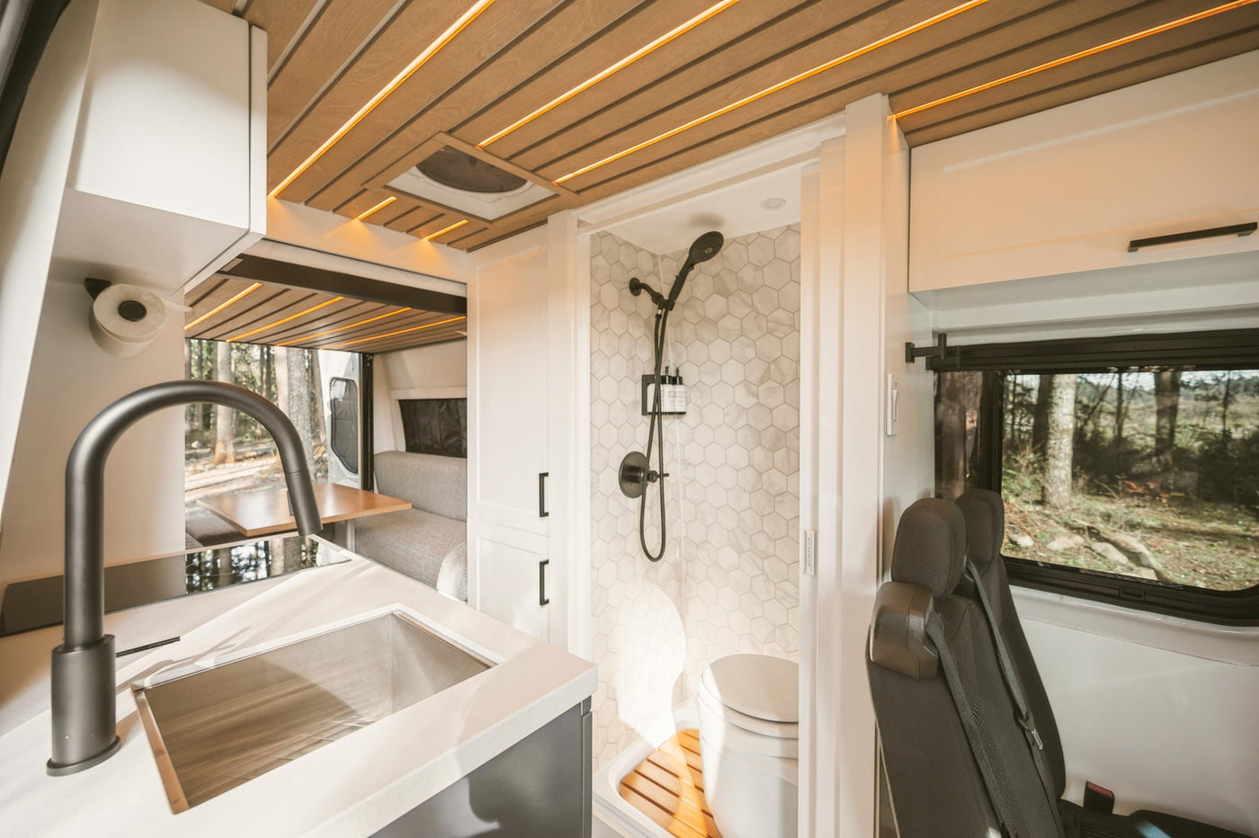 RV rental interior: modern kitchen, hexagonal tile shower, and cozy dinette in a compact camper van. — photo 18