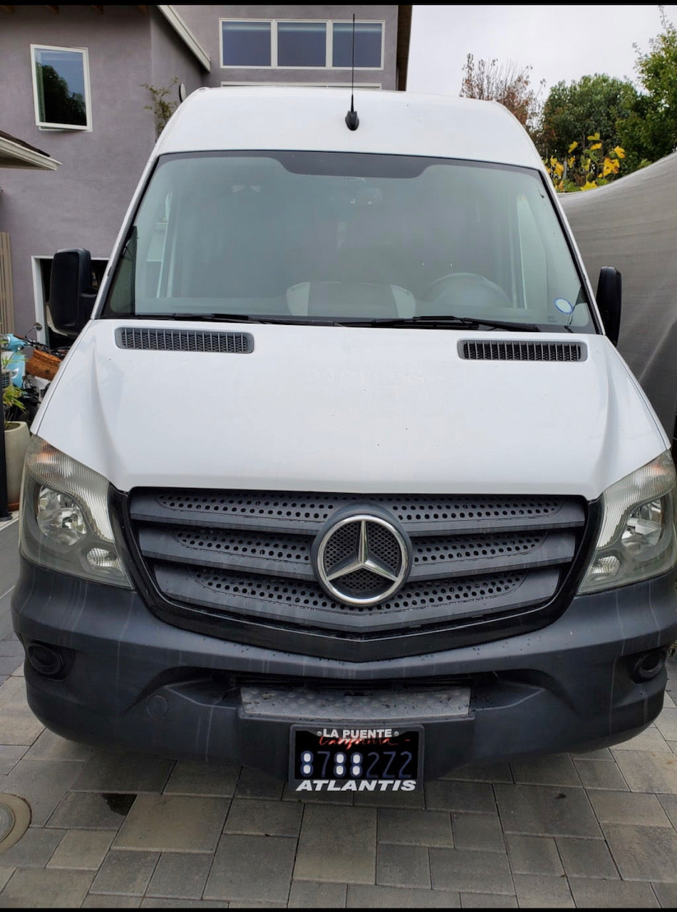 Front view of a white Mercedes-Benz Sprinter van, perfect for your next RV rental adventure, parked on a paved driveway.