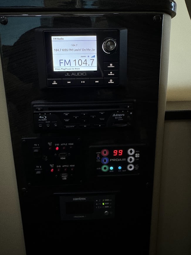 RV rental control panel shows JL Audio radio, Blu-ray, climate (99°F), & Xantrex power monitoring for passenger comfort. — photo 11