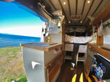 Interior of an RV rental: a cozy camper van with a stunning ocean view from the open door, showcasing the ultimate van life experience.
