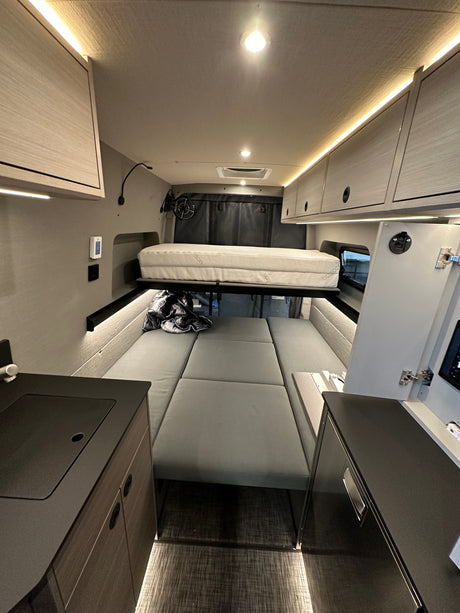 Modern RV rental interior, showcasing a versatile layout with a stowed bed, bench seating, and ambient strip lighting.