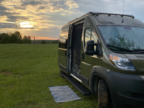 Green rv rental van parked in a grassy field at sunset