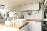 This rv rental shows a modern camper van interior with a compact kitchenette, bed, and smart storage for on-the-go living.