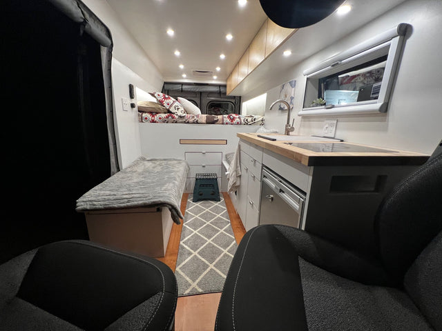  dark RV rental van rests on a scenic mountain road