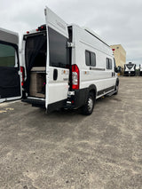 White Winnebago Solis camper van with open rear doors showing interior. Ideal RV rental for travel adventures.