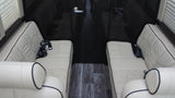 Luxurious RV rental interior features cream quilted leather seating, dark wood walls, & floor.