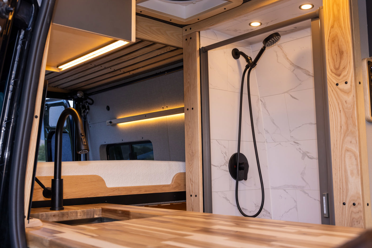 Explore this luxurious RV rental interior: modern kitchen, cozy bed, and stylish tiled shower. Ideal compact living.